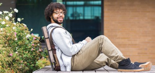 student leaning back on campus with portable easel