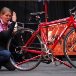 person kneeling by bike on a stand