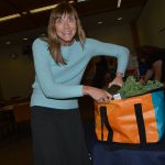 Woman placing items into orange and teal upcycled bag