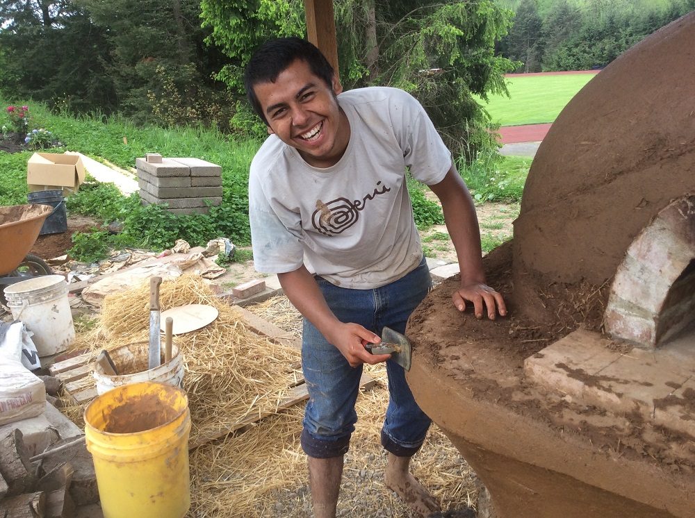 Smiling Person building cob oven