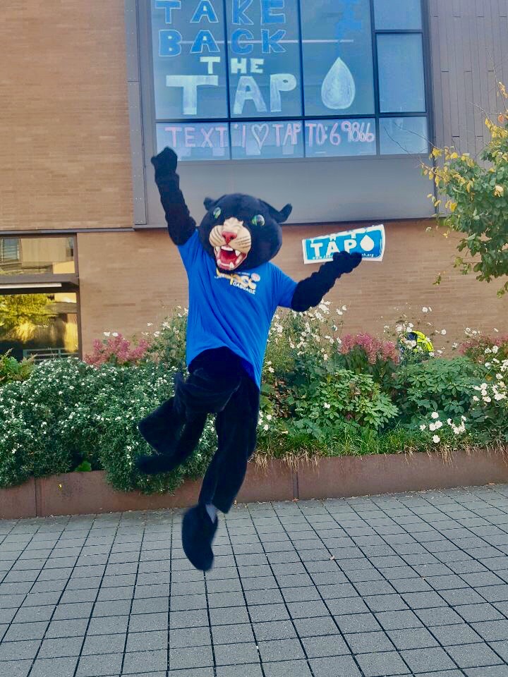 Poppie jumping with Take Back the Tap sign