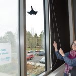 Woman pulls window shades closed.