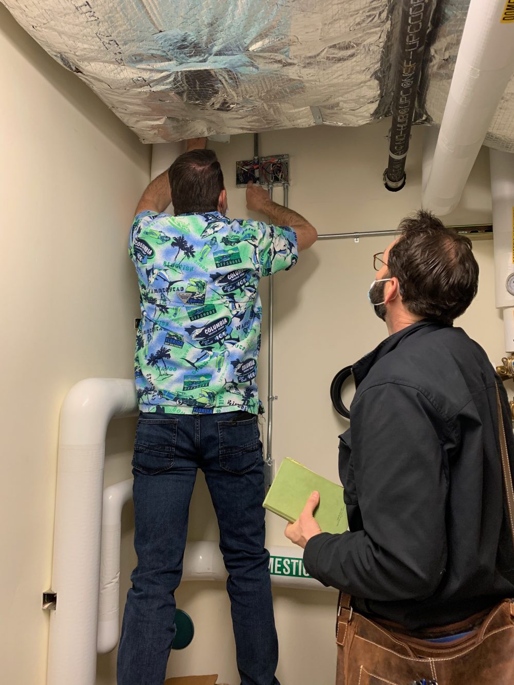 Larry Osborn, FMS Manager, and Dusty Farrell, Energy Trust of Oregon staff, check a domestic hot water relay in the SE Learning Commons Library