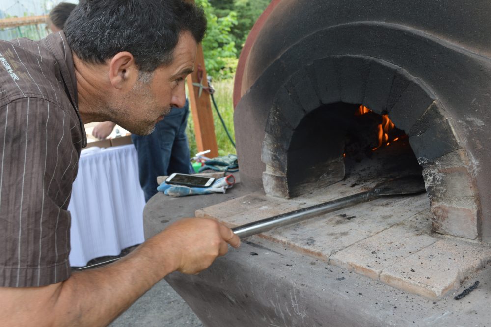 SPARC member making pizza in cobb oven