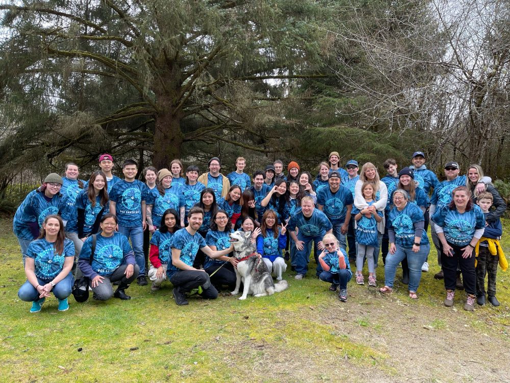 80 people gathered for a photo at a beach clean up in blue earth shirts