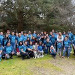 80 people gathered for a photo at a beach clean up in blue earth shirts