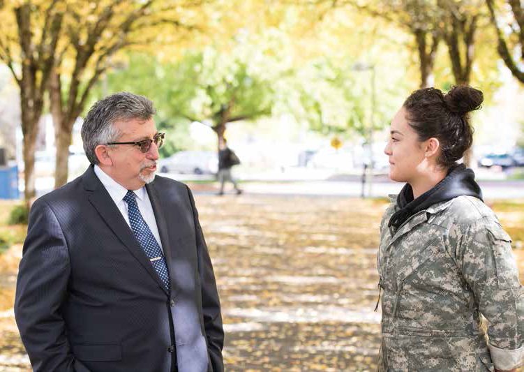 Campus president chats with student in camo jacket