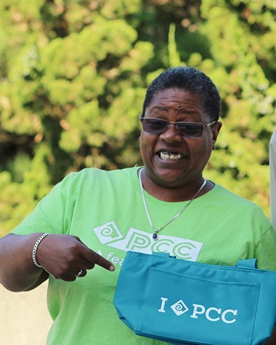 Woman holding PCC tote bag and wearing a PCC t-shirt