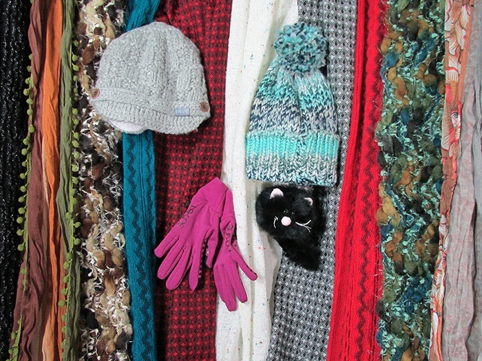 Very cluttered image of hats on top of scarves - you can't tell what the picture is supposed to be of