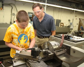 Ben Baldwin, 14, from Catlin Gabel gets a little help from Nathan Beste (right) of FEI Company.