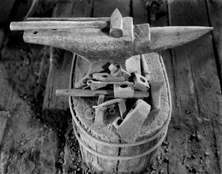 'Anvil and Hammer' from Loren Nelon's exhibit 'Portal to the Past,' featuring black and white photographs of a preserved blacksmith's shop from the 1960s.