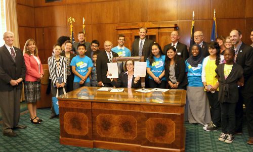 Gov. Kate Brown signs HB 3063 into law with PCC's Future Connect contingent surrounding her.