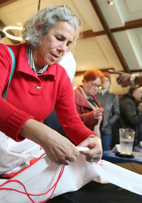 A visitor adds a stitch to a new belt that will be part of a community project.