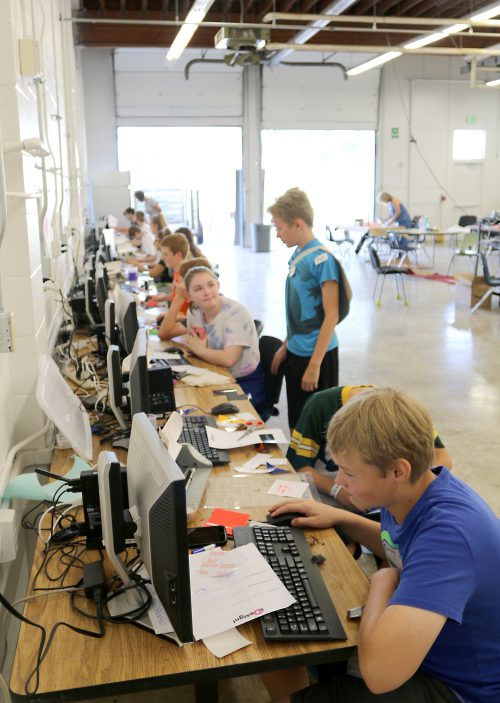 Held at a former auto shop behind Scappoose High School, Portland Community College faculty showed students how to design and print custom decals, etched glass, pop-up cards and charms that showcased their company’s logo